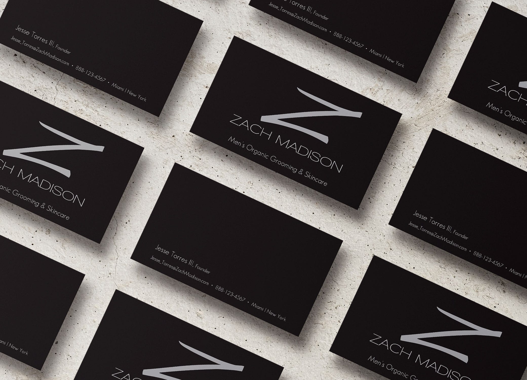 Zach Madison black business cards with metallic 'Z' arranged in slanted rows showing front and back on granite backdrop.