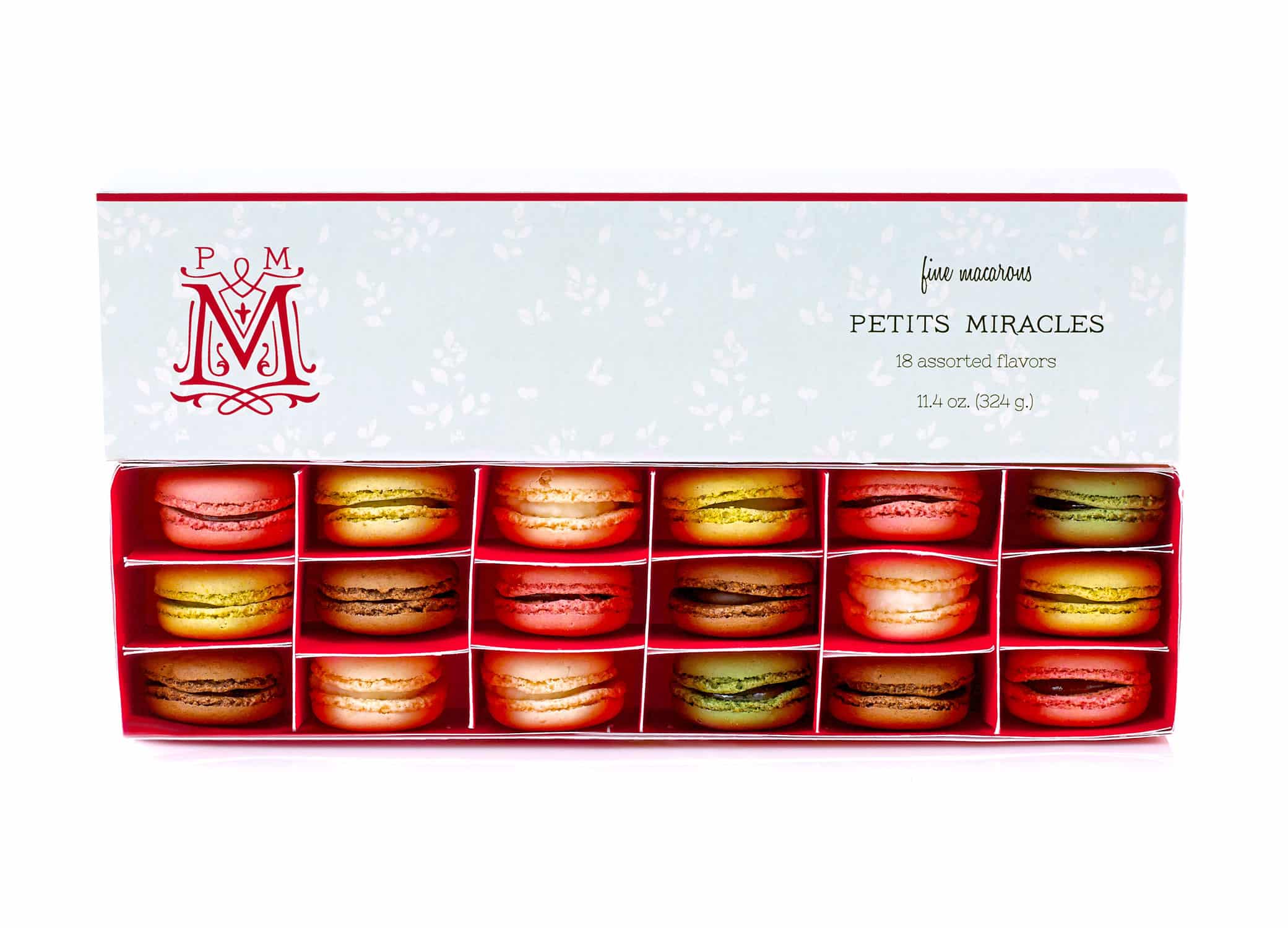 Petits Miracles packaging design with macaroons in the box and swirls around "M" icon next to type.