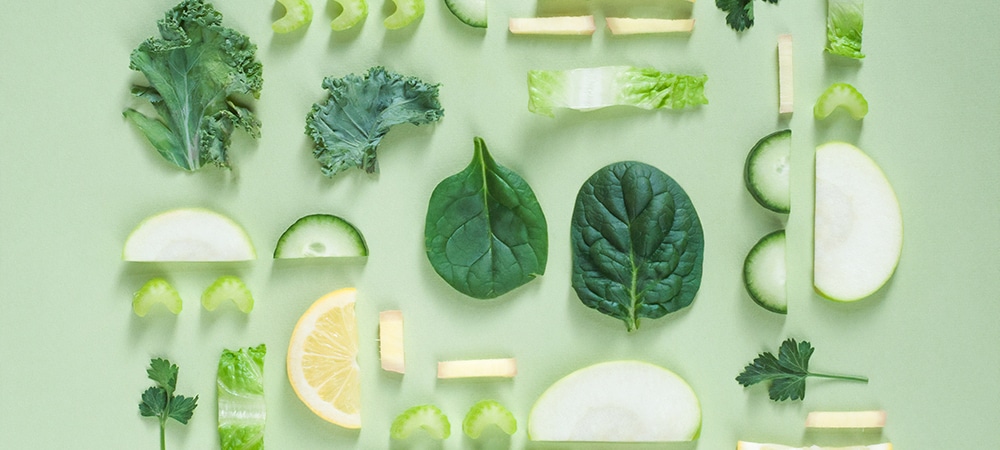 Slices of different types of vegetables and some fruits all ranging in colors of green.