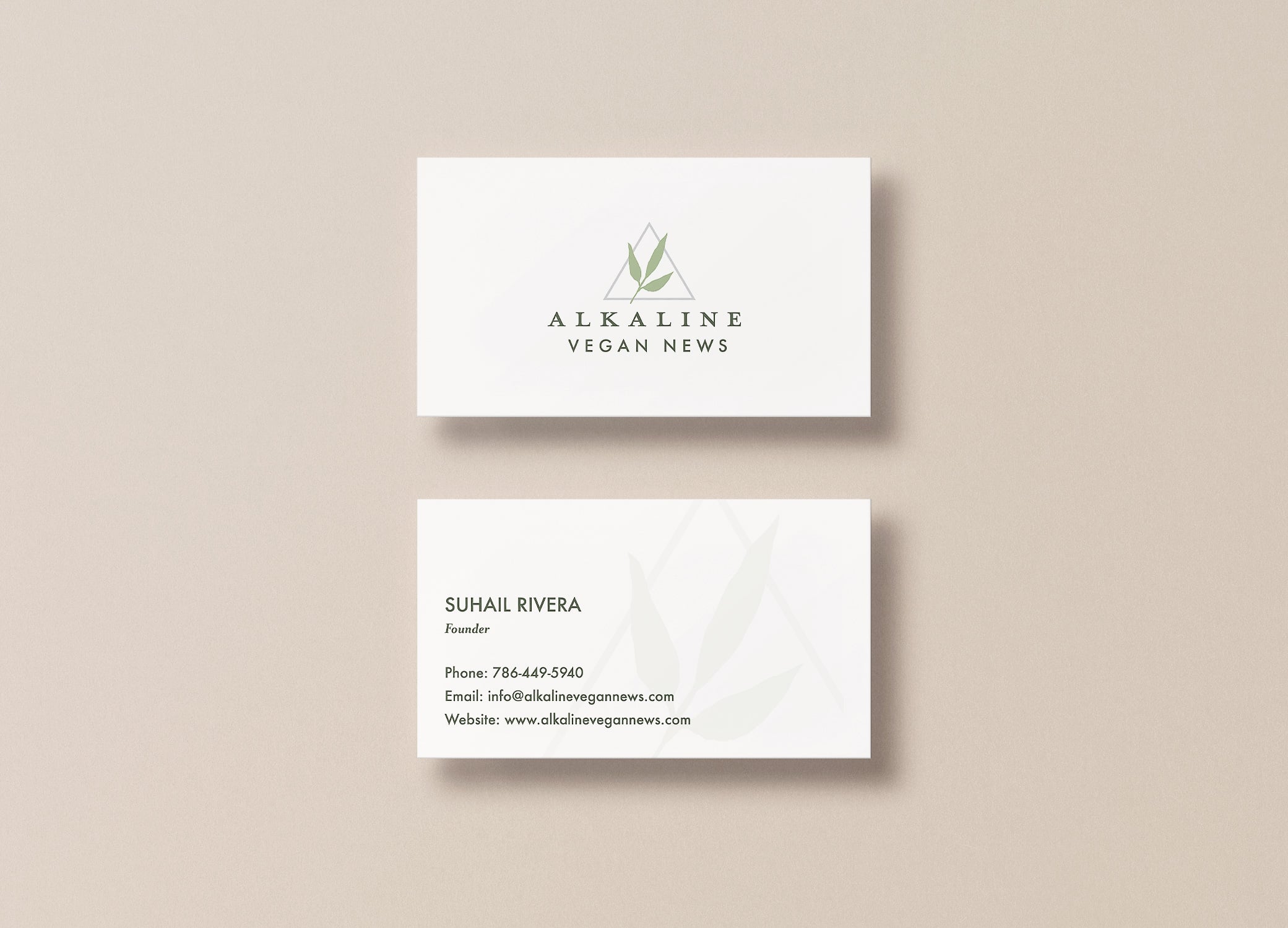 Alkaline Vegan News business cards arranged in stacks to show front and back view against a light beige backdrop.