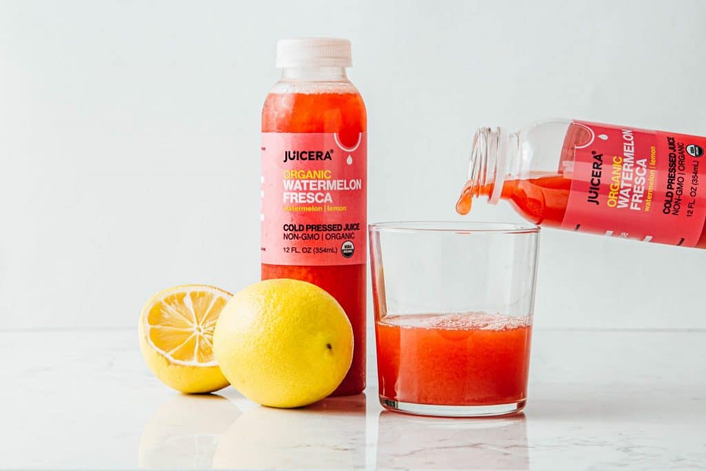 Juicera juice brand product photography showcasing the juice pouring into a glass with cut lemon decoration.