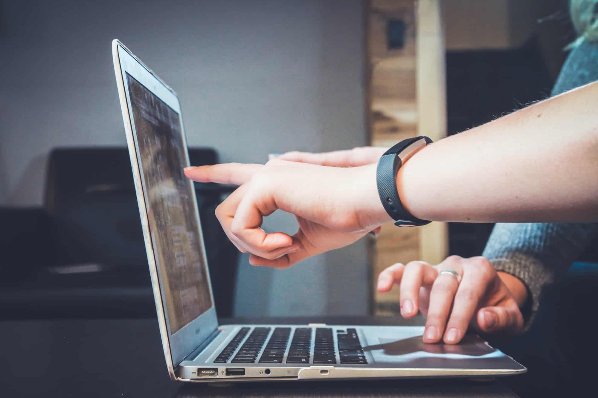 Business entrepreneurs analyzing something on a laptop pointing at the screen.