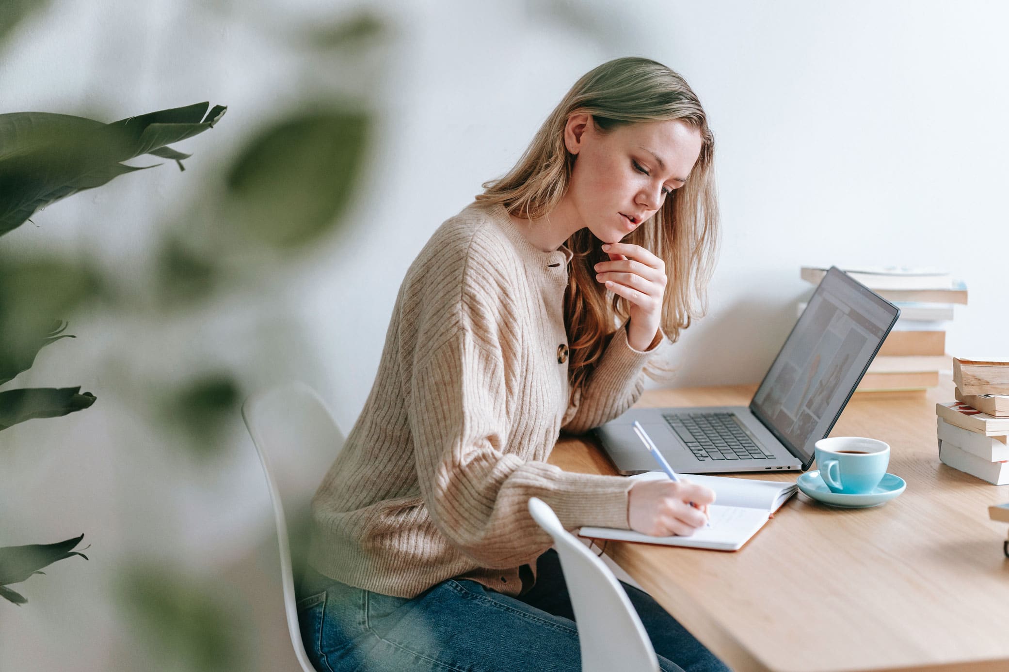 Woman finding a sales representative online using laptop and notebook for notes.