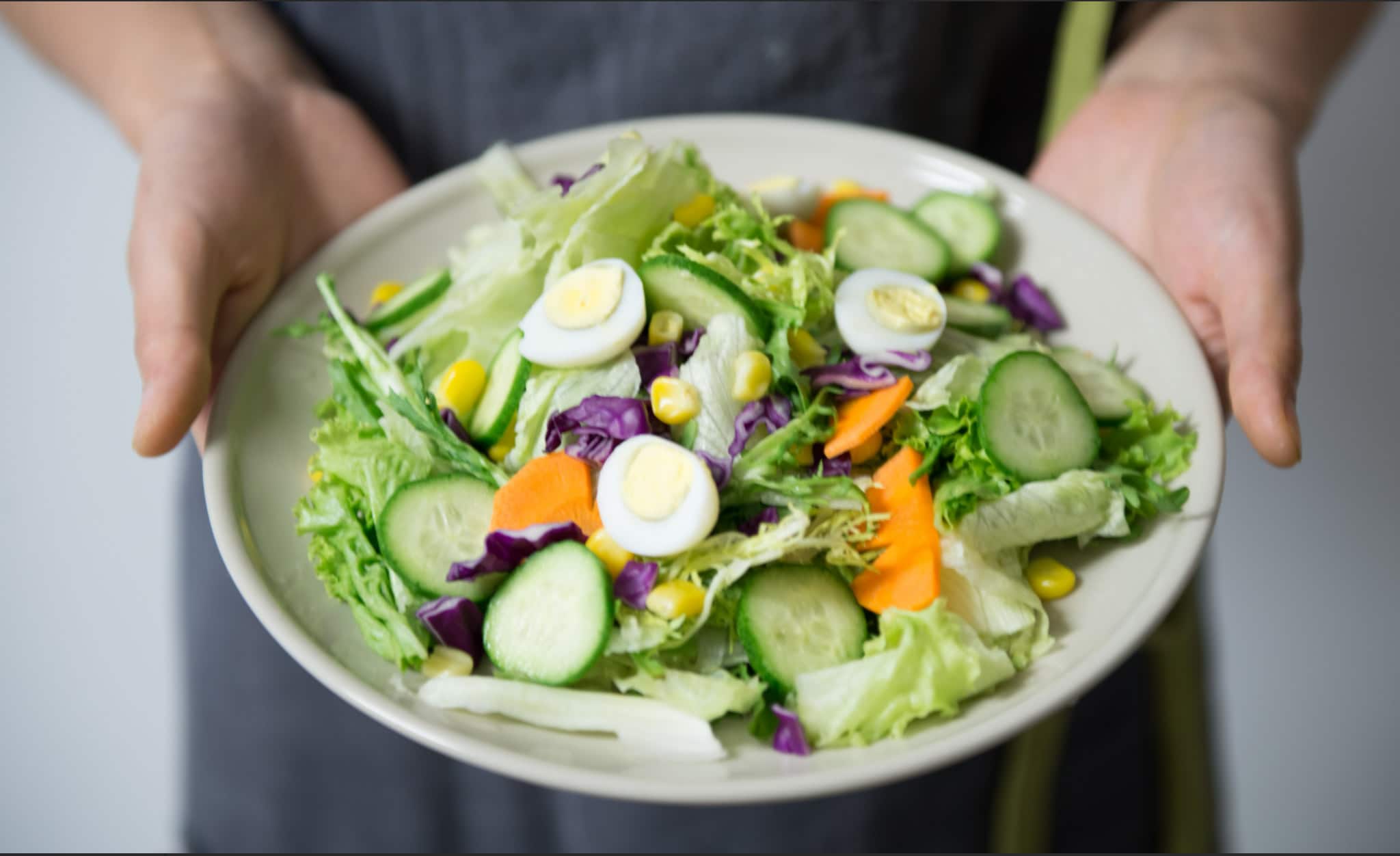 Paleo pegan diet salad with vegetable ingredients of lettuce, eggs, carrots, and corn.