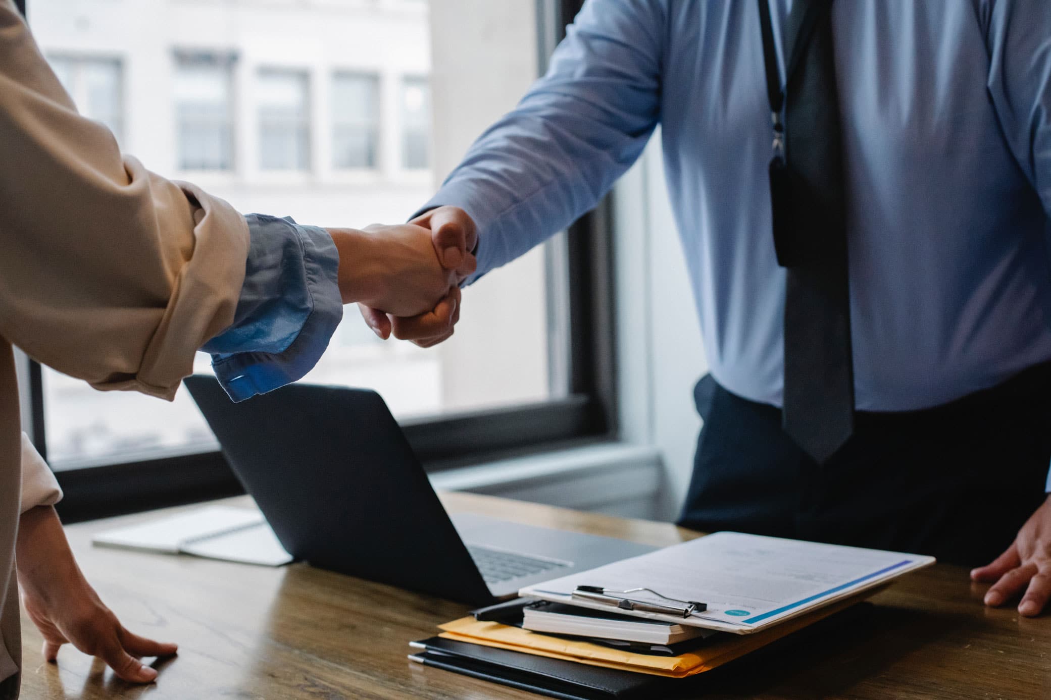 Two people shaking hands in office setting making a business deal.