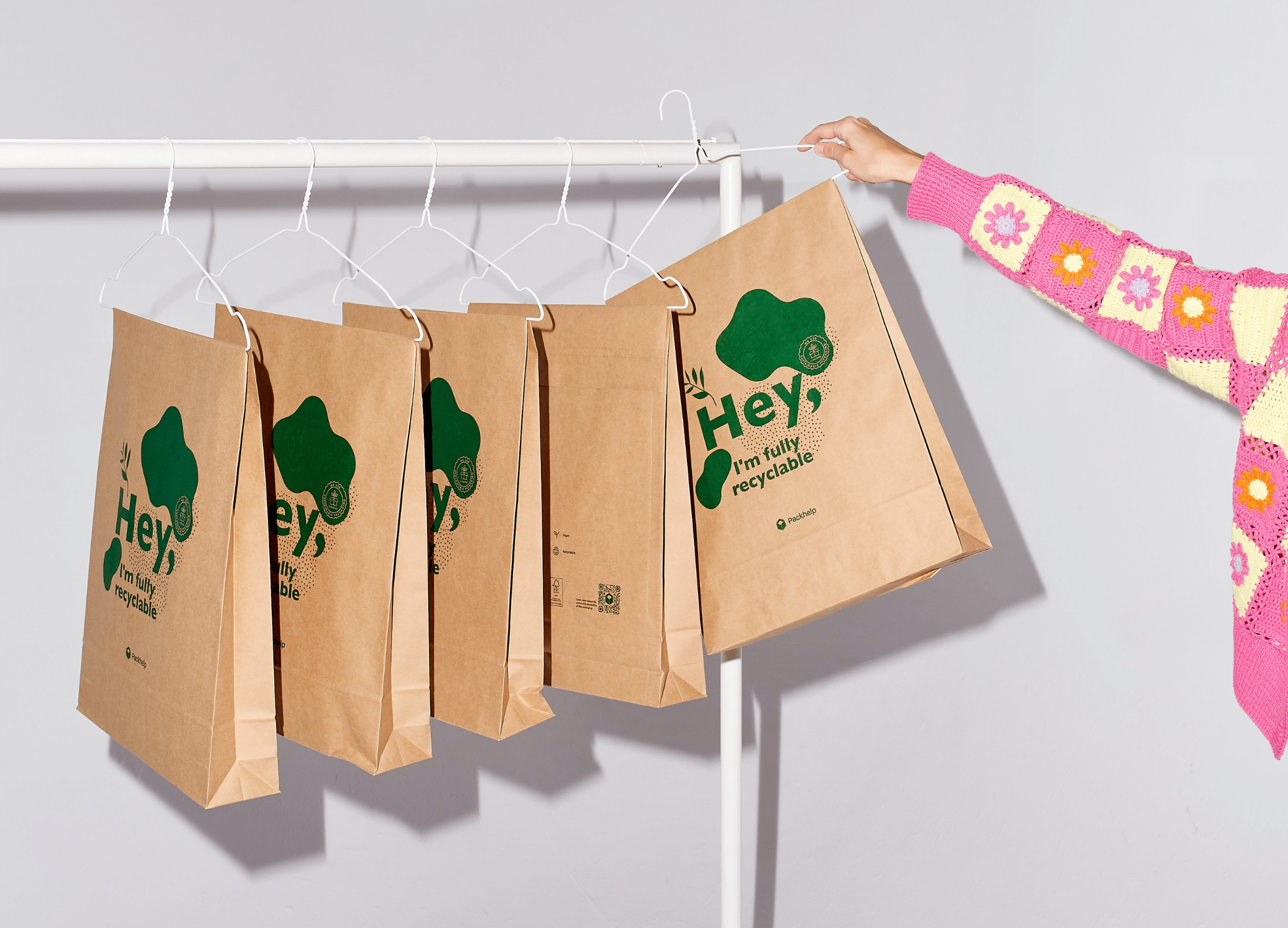 Woman taking a sustainably, recyclable bag off rack.