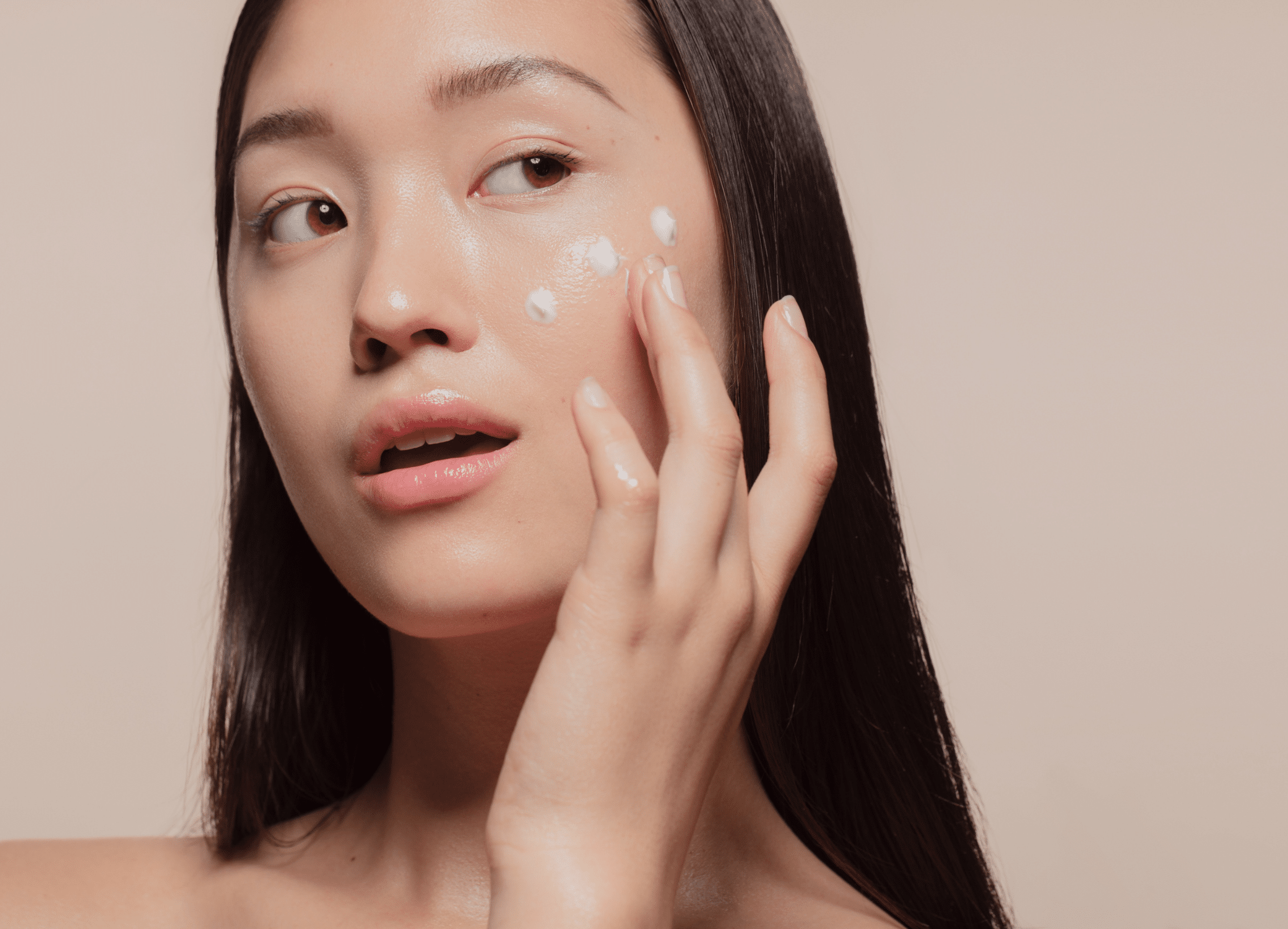 Skincare industry trends that influence the female consumer; woman applying moisturizer to face.