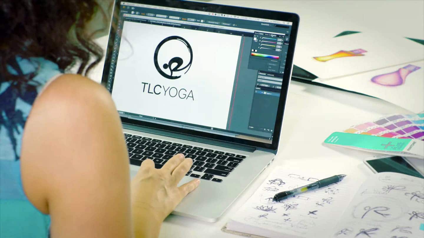 Lauren working on the TLC Yoga logo with sketches and inspirational materials on her desk.