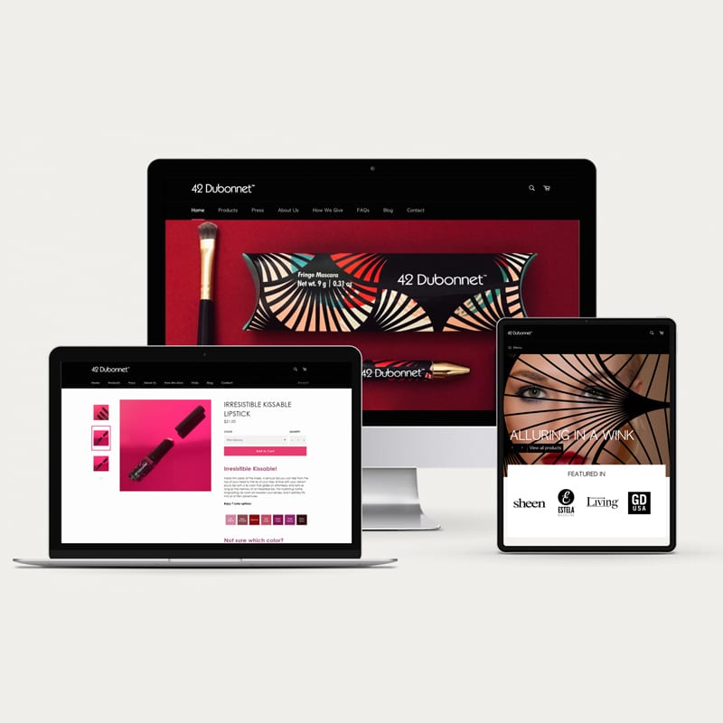 Makeup Packaging Design: 42 Dubonnet responsive website design for desktop. laptop and mobile. The homepage design is in black with hero image of makeup packages splashed against burgundy backdrop.