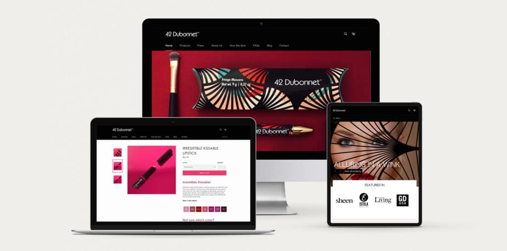 Launch a Beauty Beauty: 42 Dubonnet responsive website design for desktop. laptop and mobile. The homepage design is in black with hero image of makeup packages splashed against burgundy backdrop.