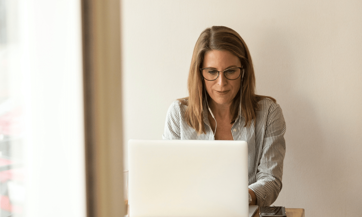 Woman entrepreneur working on laptop in office with headphones in.