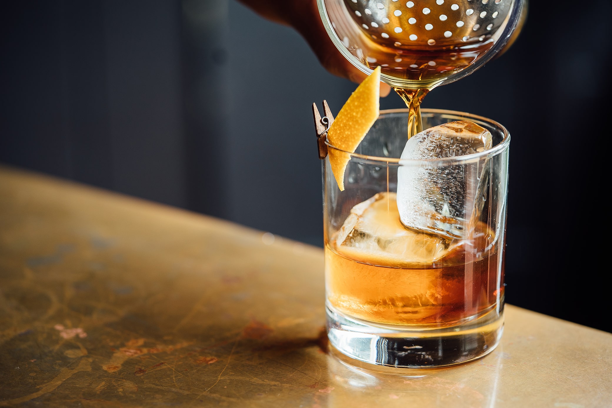How Can I Sell Alcohol Online? Showing a glass with ice cubes and bourbon and an orange slice.