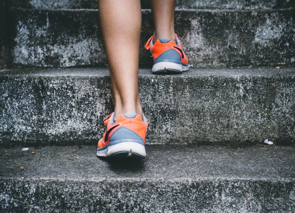 how to avoid burnout as an entrepreneur: make progress with small steps. Woman walking up steps.