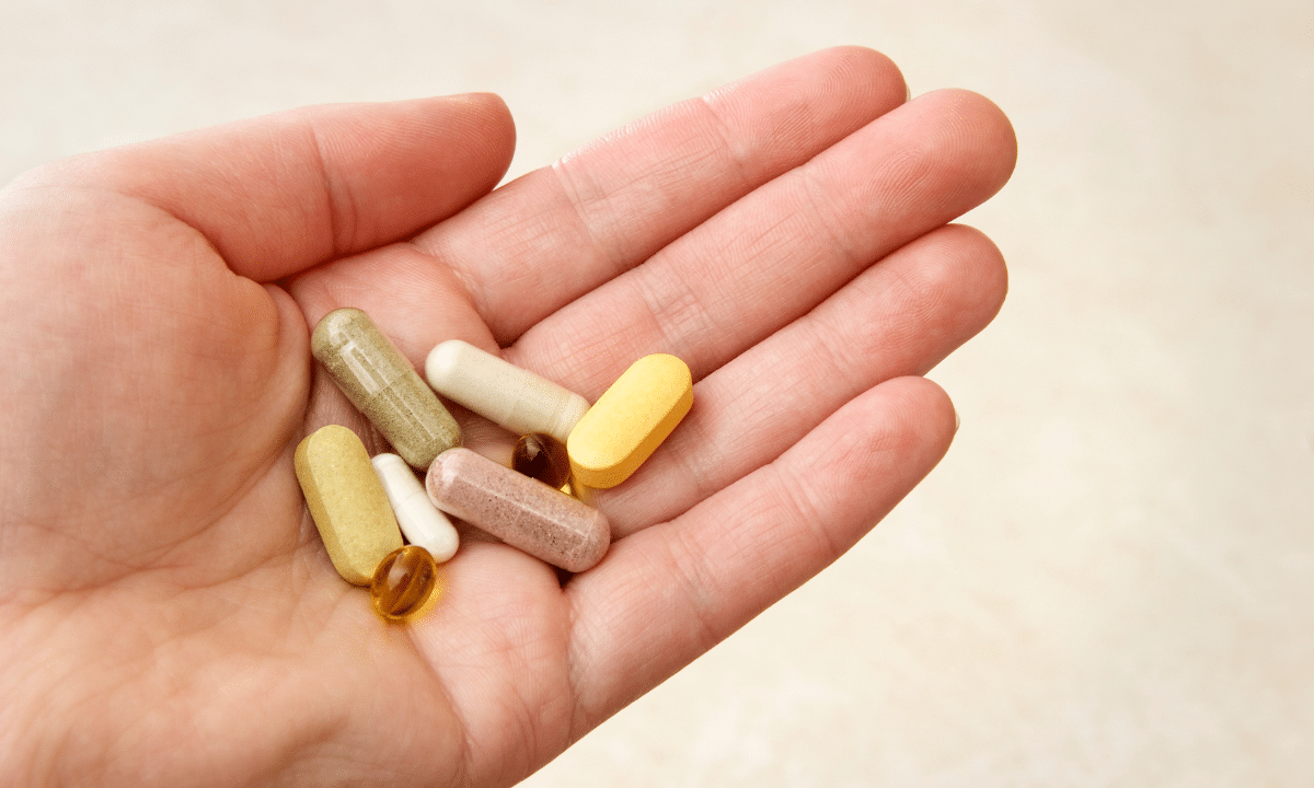 Different types of dietary supplements placed palm of open hand.