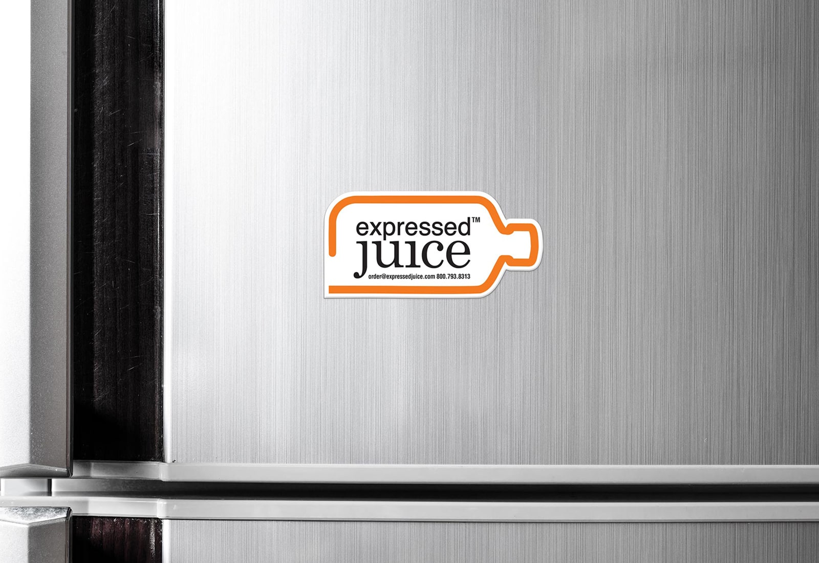 Expressed Juice magnet on refrigerator door of the sideways bottle outline in orange with black and white logo inside.