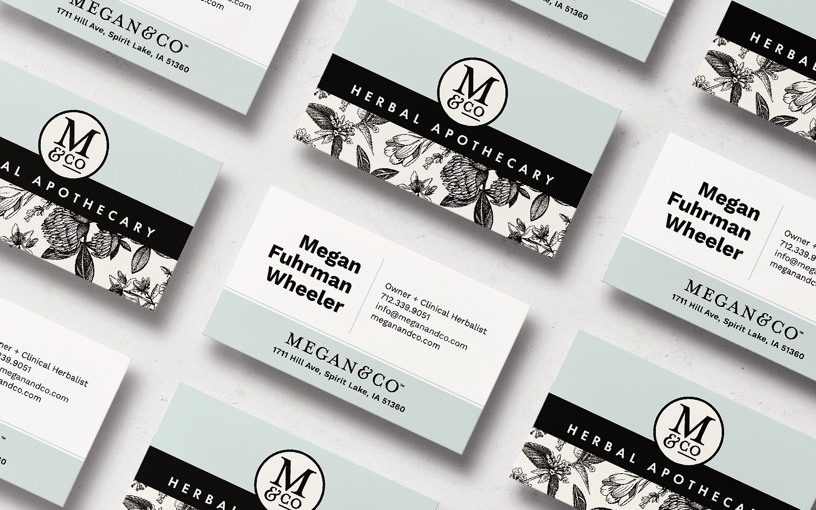 Megan Co the Herbal Apothecary business cards in black, white, and dusty blue with floral illustrations and a monogrammed "M & Co.